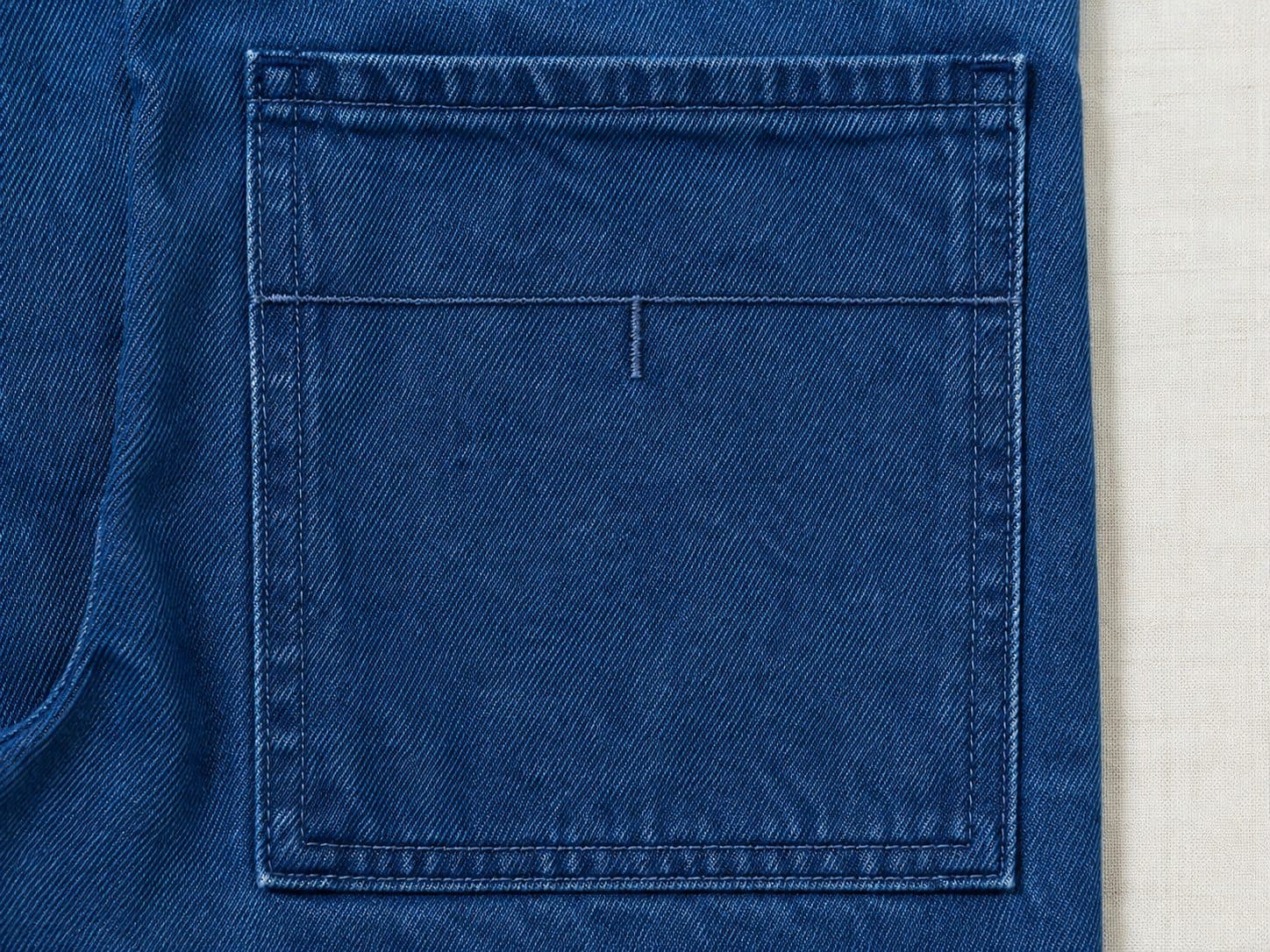 Macro of a plain back pocket with one straight horizontal line of stitching and a short vertical tick descending from its centre