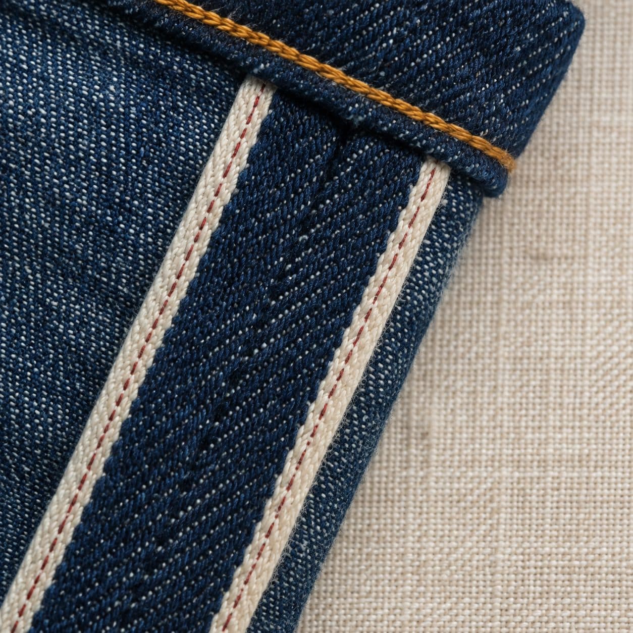 Macro of the finished edge band along the outer seam of a denim trouser leg